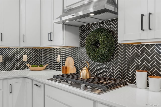 kitchen with stainless steel gas stovetop, white cabinetry, exhaust hood, and decorative backsplash