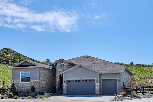 547 Scrubjay Cir, Castle Rock, CO 80104 - view of front facade featuring a garage, stone siding, a shingled roof, and driveway
