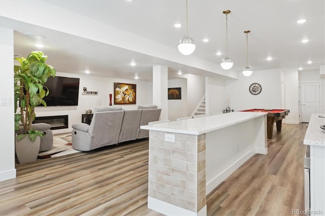 547 Scrubjay Cir, Castle Rock, CO 80104 - kitchen with light wood-style floors, an island with sink, light stone counters, pendant lighting, and recessed lighting