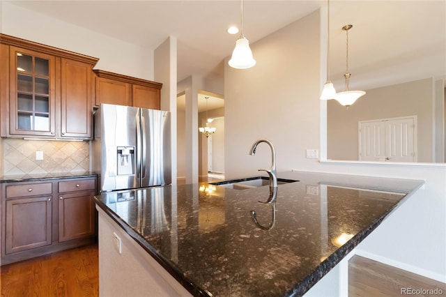 kitchen with wood finished floors, brown cabinetry, stainless steel fridge with ice dispenser, a sink, and tasteful backsplash