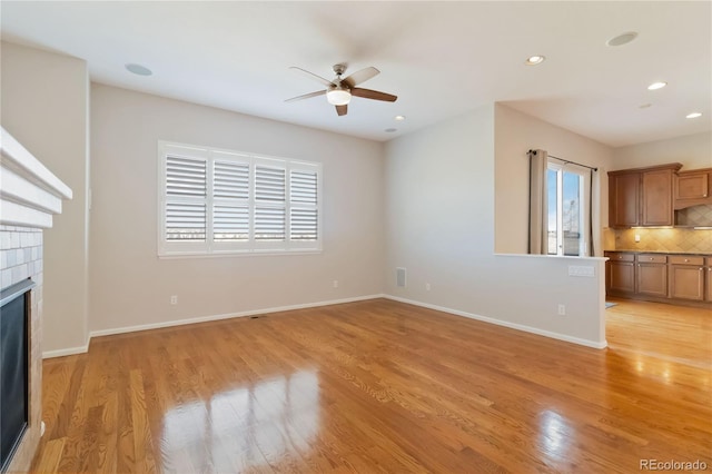 unfurnished living room featuring a glass covered fireplace, recessed lighting, light wood-style floors, and baseboards