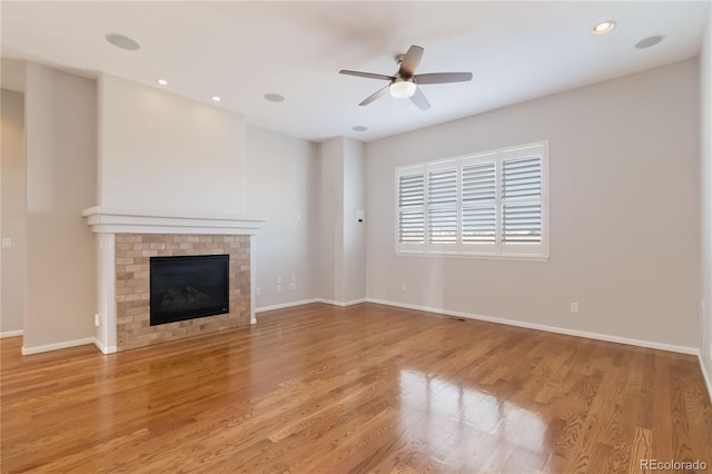 unfurnished living room featuring light wood finished floors, a brick fireplace, baseboards, recessed lighting, and a ceiling fan