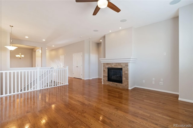 unfurnished living room featuring a brick fireplace, recessed lighting, wood finished floors, and baseboards