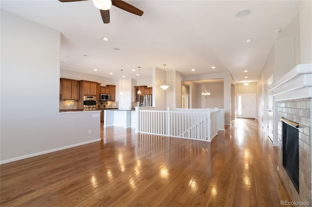 unfurnished living room featuring recessed lighting, wood finished floors, baseboards, and a tile fireplace