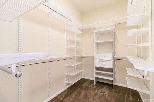 spacious closet featuring visible vents and dark colored carpet