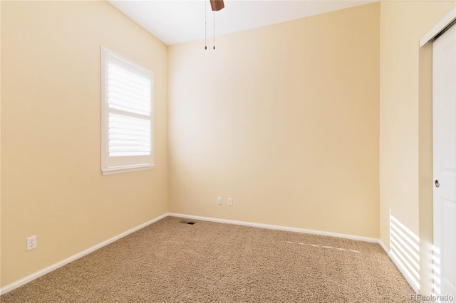 carpeted spare room with baseboards, visible vents, and ceiling fan