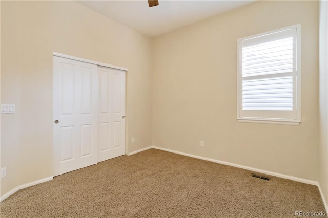 unfurnished bedroom featuring a closet, visible vents, baseboards, and carpet floors