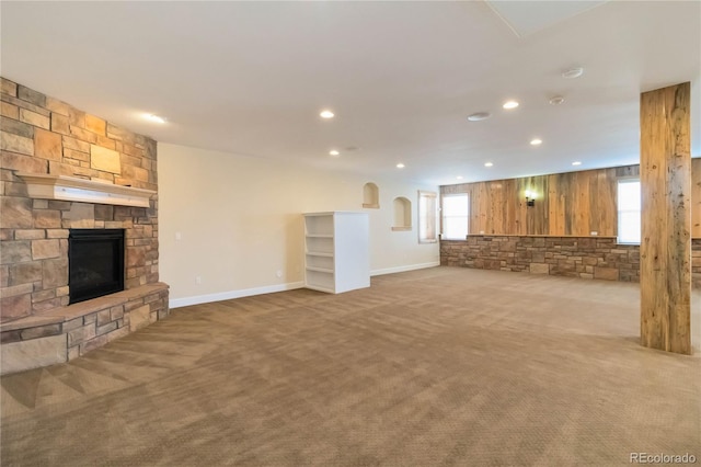 unfurnished living room with a stone fireplace, recessed lighting, and carpet