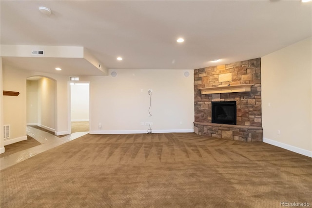 unfurnished living room featuring visible vents, recessed lighting, a stone fireplace, carpet flooring, and baseboards