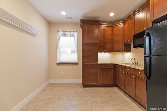 kitchen with light stone counters, visible vents, baseboards, a sink, and black appliances