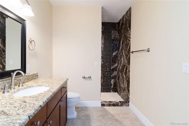 bathroom featuring baseboards, toilet, vanity, and a tile shower