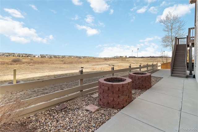 view of yard featuring a rural view, a fire pit, stairs, and fence