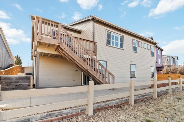 view of side of property featuring stairway, a wooden deck, and fence