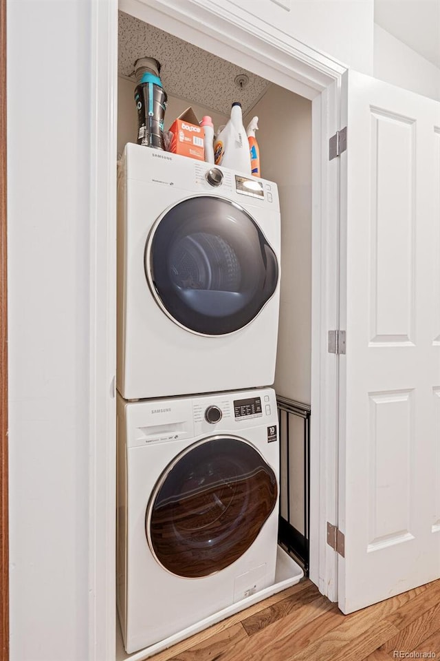 washroom featuring a textured ceiling, stacked washer / dryer, and wood-type flooring