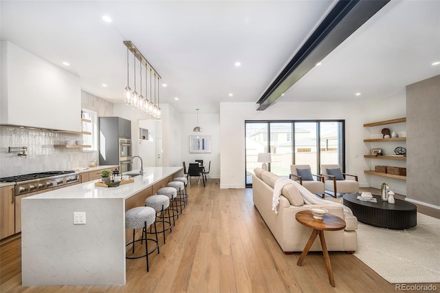 kitchen featuring a kitchen breakfast bar, light hardwood / wood-style flooring, pendant lighting, and a kitchen island with sink