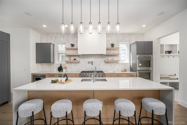 kitchen featuring a kitchen island with sink, tasteful backsplash, and gray cabinets