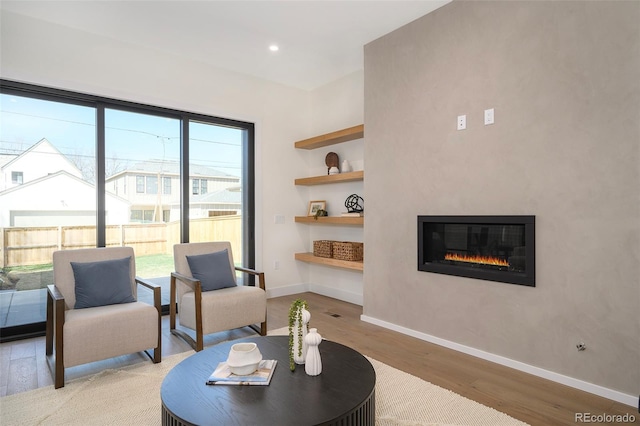 living area featuring built in features, light hardwood / wood-style flooring, and plenty of natural light