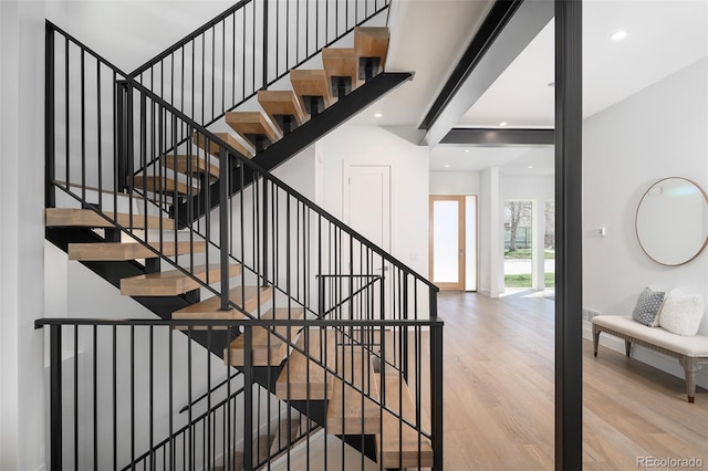 stairway featuring beam ceiling and light wood-type flooring