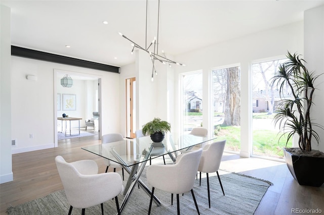 dining space featuring plenty of natural light, light hardwood / wood-style floors, and an inviting chandelier