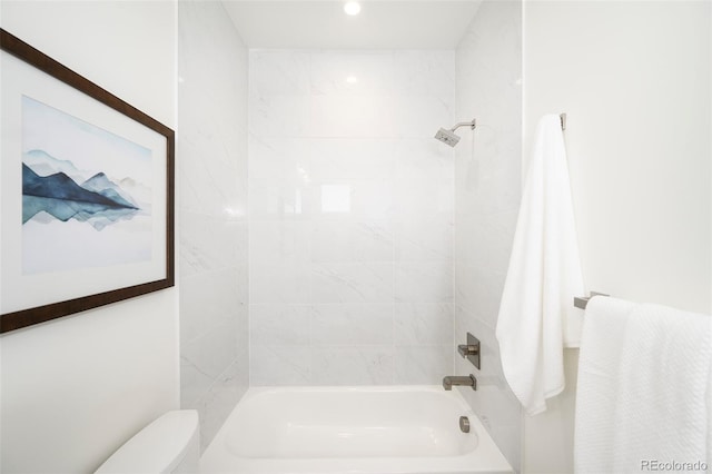 bathroom featuring toilet and tiled shower / bath