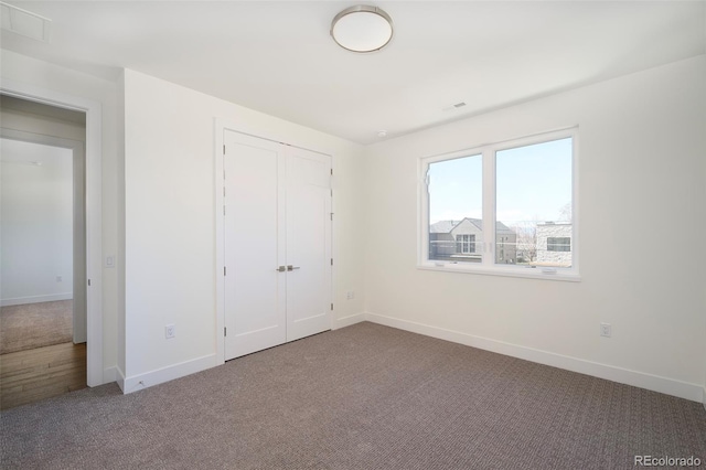 unfurnished bedroom featuring a closet and dark carpet