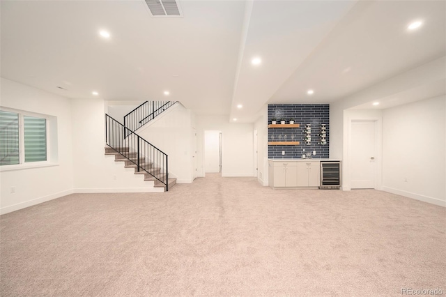 unfurnished living room with wine cooler and light colored carpet