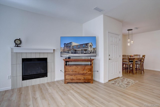 living room with a fireplace, wood finished floors, visible vents, and baseboards