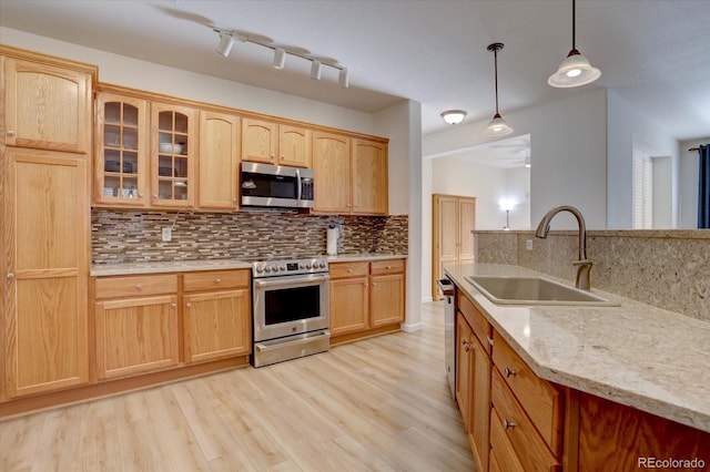 kitchen with stainless steel appliances, light wood-style floors, glass insert cabinets, and a sink