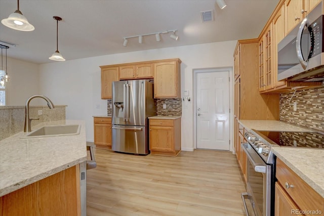 kitchen featuring pendant lighting, visible vents, appliances with stainless steel finishes, a sink, and light wood-type flooring