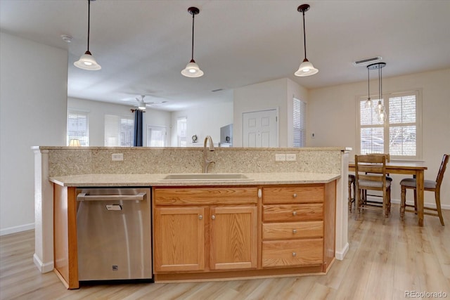 kitchen featuring a sink, plenty of natural light, light wood-style flooring, and stainless steel dishwasher