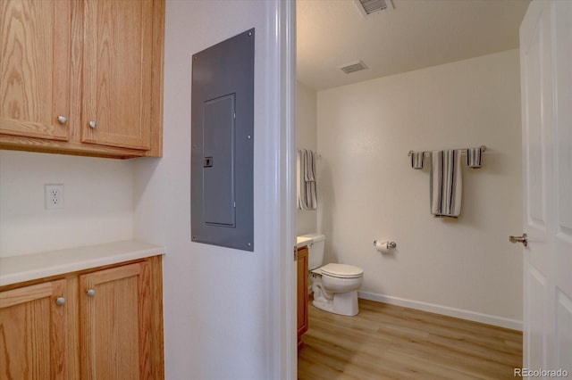 bathroom featuring electric panel, visible vents, toilet, wood finished floors, and vanity