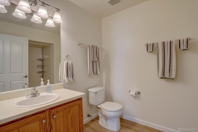 bathroom featuring a shower, visible vents, toilet, vanity, and wood finished floors