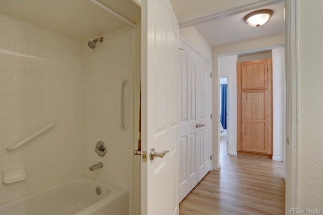 bathroom featuring washtub / shower combination and wood finished floors