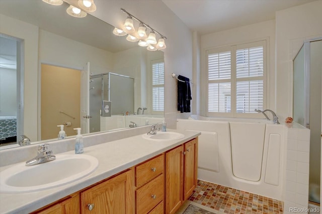 ensuite bathroom with double vanity, a stall shower, a sink, and a bath