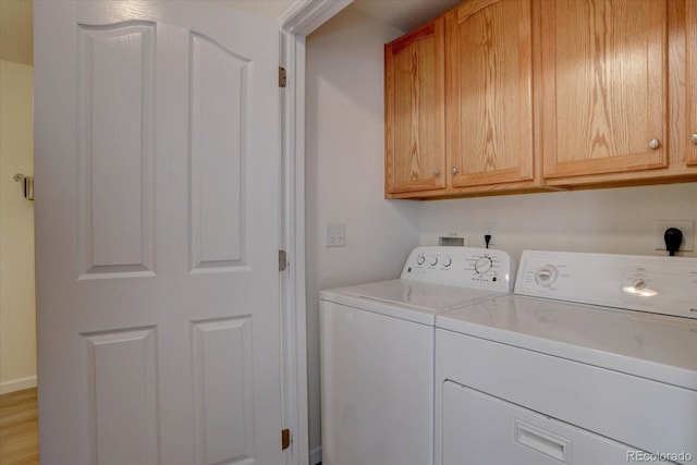 clothes washing area with washing machine and dryer and cabinet space