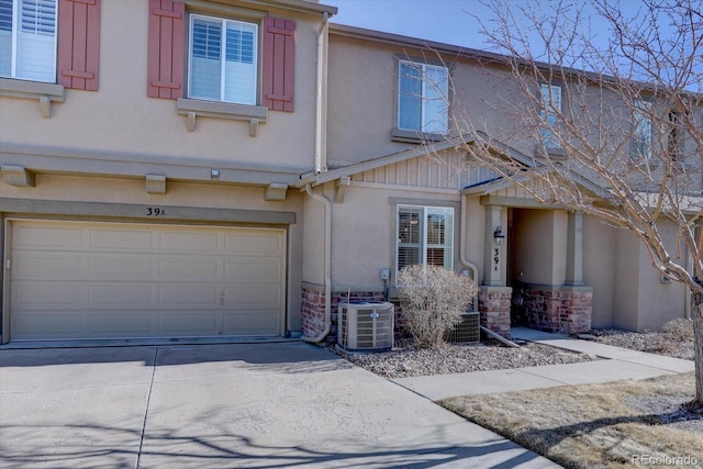 view of front of house with an attached garage, central AC unit, concrete driveway, and stucco siding