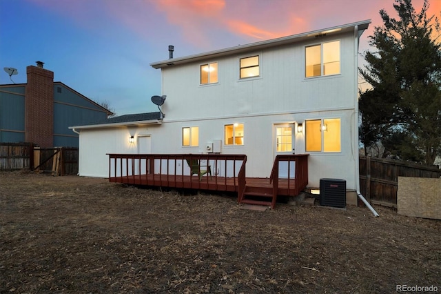 back of house at dusk with a deck, fence, and central air condition unit