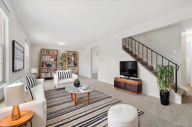 carpeted living room featuring visible vents and stairway