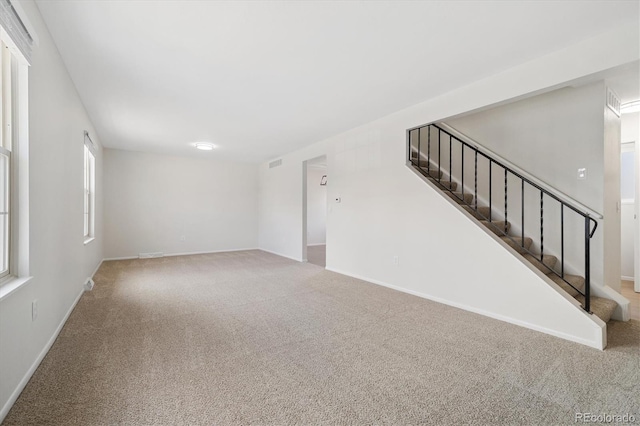 unfurnished living room featuring carpet floors, baseboards, stairs, and visible vents