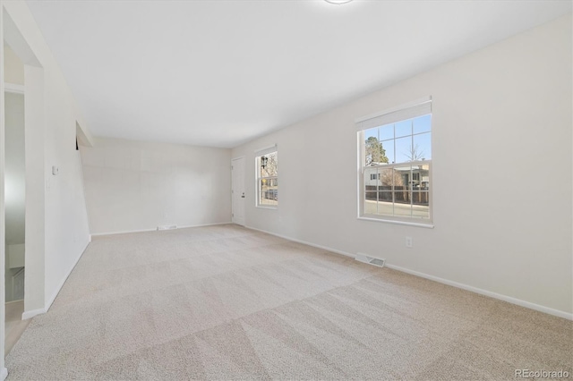 unfurnished room with carpet floors, visible vents, and baseboards