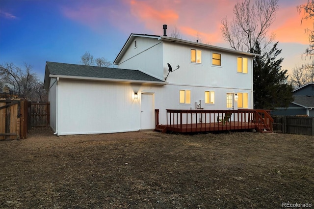 back of property at dusk featuring a fenced backyard and a wooden deck