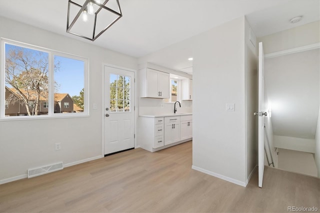 interior space featuring light wood-type flooring, visible vents, and baseboards