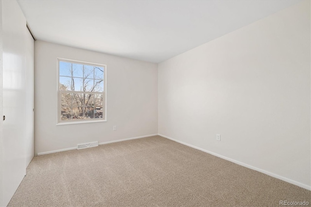 spare room featuring carpet, visible vents, and baseboards