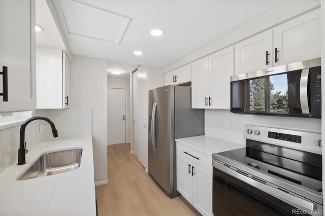 kitchen featuring a sink, white cabinets, light countertops, appliances with stainless steel finishes, and light wood-type flooring