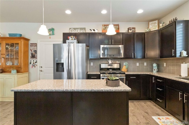 1640 Aspen Meadows Cir, Federal Heights, CO 80260 - kitchen featuring appliances with stainless steel finishes, a kitchen island, light wood-style floors, backsplash, and decorative light fixtures