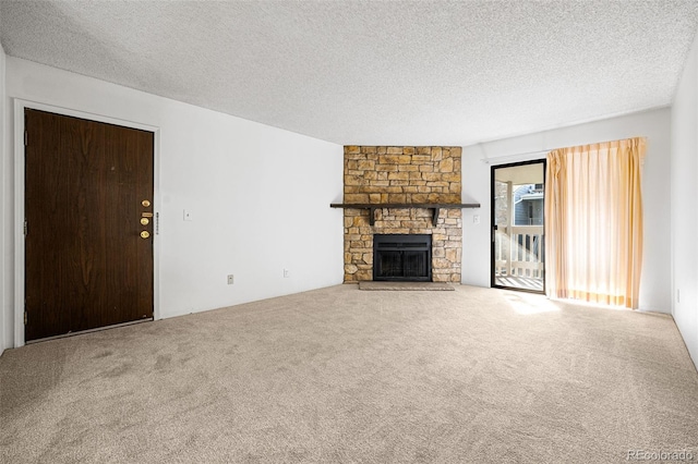 unfurnished living room featuring a textured ceiling, a stone fireplace, and carpet flooring