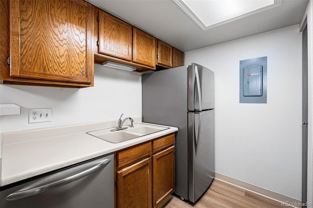 kitchen with light wood-type flooring, stainless steel appliances, sink, and electric panel