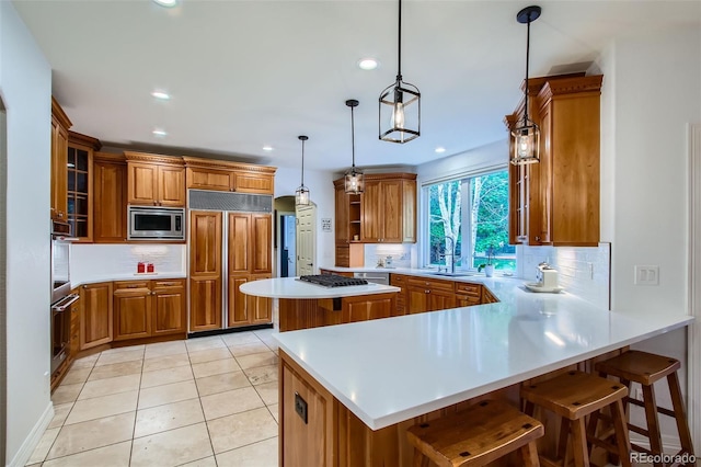 7355 Nile St, Arvada, CO 80007 - kitchen featuring built in appliances, brown cabinetry, a peninsula, backsplash, and recessed lighting