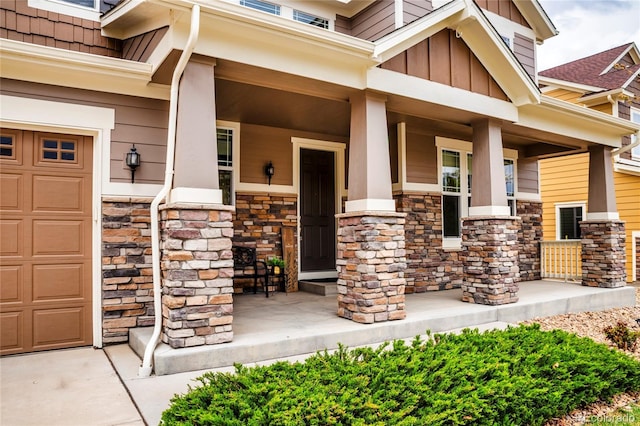 property entrance with a porch, board and batten siding, a garage, and stone siding