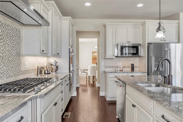 kitchen featuring range hood, stainless steel appliances, a sink, white cabinetry, and recessed lighting